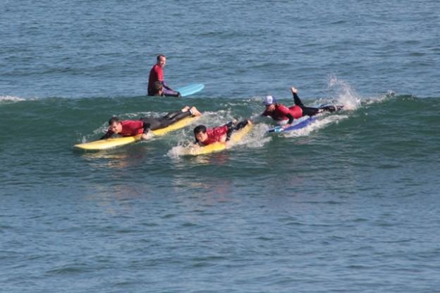 Surf instructor Nina Ke'alohi Dodge, in cap, pushes Pil Nam into a wave. Next to him Bragi Sveinsson paddles hard while Ryan Smith looks on. Chip Scheuer photo.