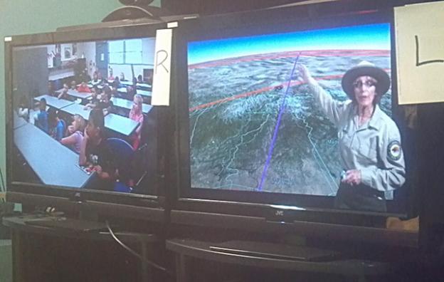 PORTS instructor Vonnie Lempke, right, delivers a videoconferenced lesson about butterflies to a second-grade classroom from a makeshift studio at Seacliff State Beach. The "L" and "R" signs help Lempke, standing off-camera, navigate the green screen as a TV meteorologist does.