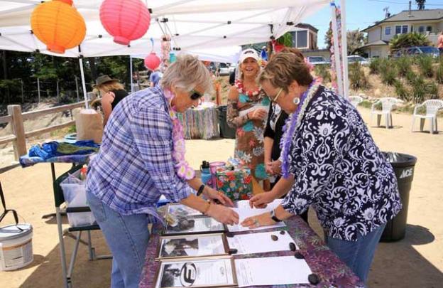 Rikki Bell and Sally setting up the auction bid sheets w/Laureen photobombing in the background.