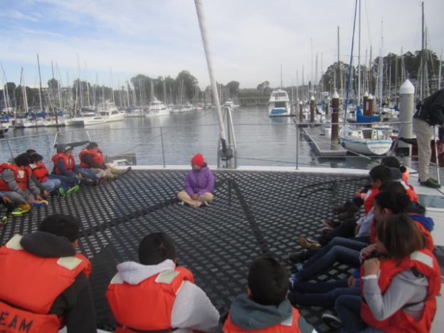 Celia Lara of O'Neill Sea Odyssey gives the students an orientation on the O'Neill Catamaran's mesh deck.