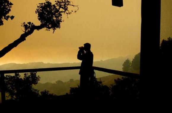 Dec. 16: C Kevin Smith scans the fires through a very smoky sky. Where the fire is next going is still very iffy. There have been multiple, very long chains of fire marching through Lower Pfeiffer. Trees exploding, propane tanks torching all night. Woof.